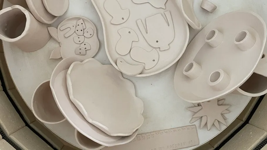 Unfired clay pottery and shapes inside kiln.