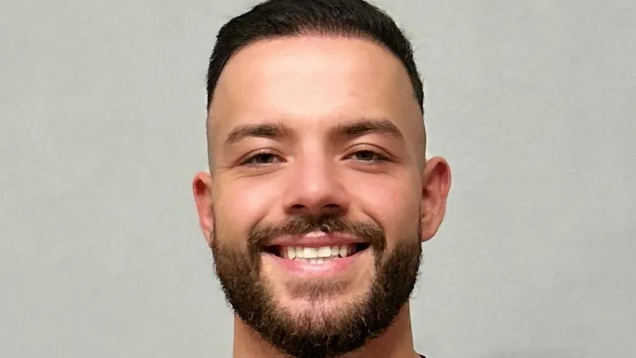 Smiling man with beard against plain background.