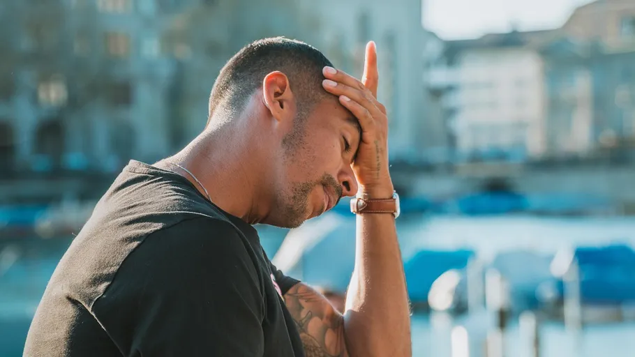 Man holding head looking stressed outside.