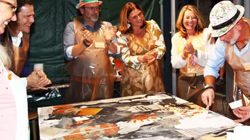 Menschen gestalten Kunst auf großer Leinwand.