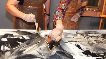 Personen malen abstrakte Kunst auf großer Leinwand.
