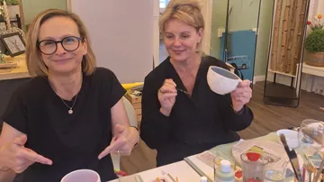 Zwei Frauen bemalen Keramik an einem Tisch.