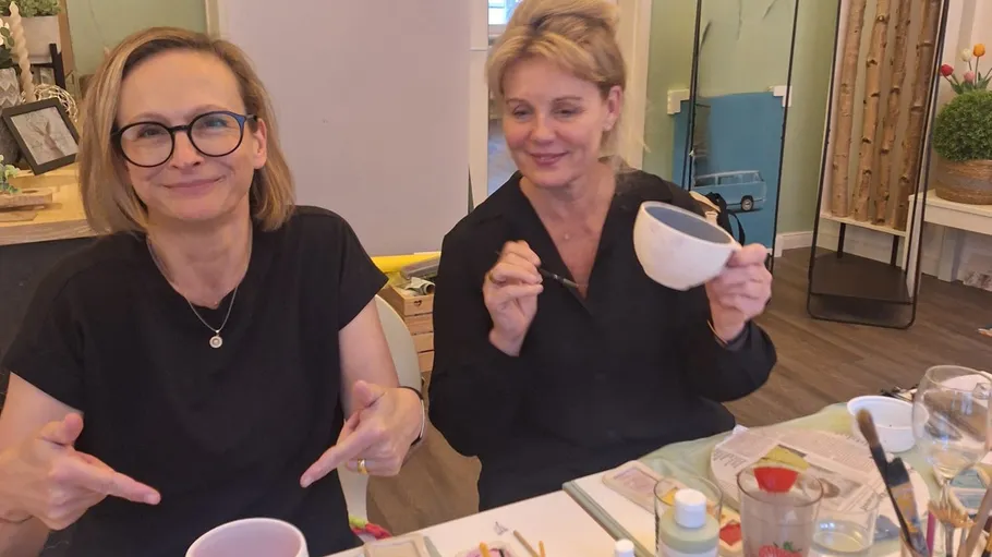 Zwei Frauen bemalen Keramik an einem Tisch.