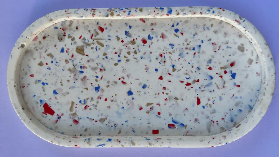 Oval tray with multicolored speckles on surface.