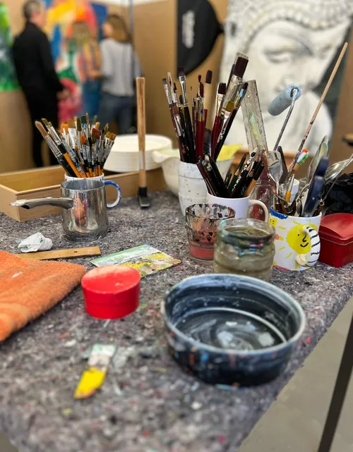 Pinsel auf Tisch im Kunststudio mit Gemälden.