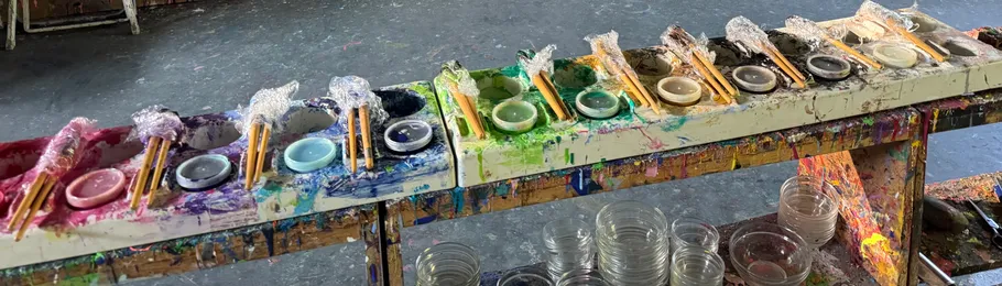 Row of colorful paint pots with brushes.