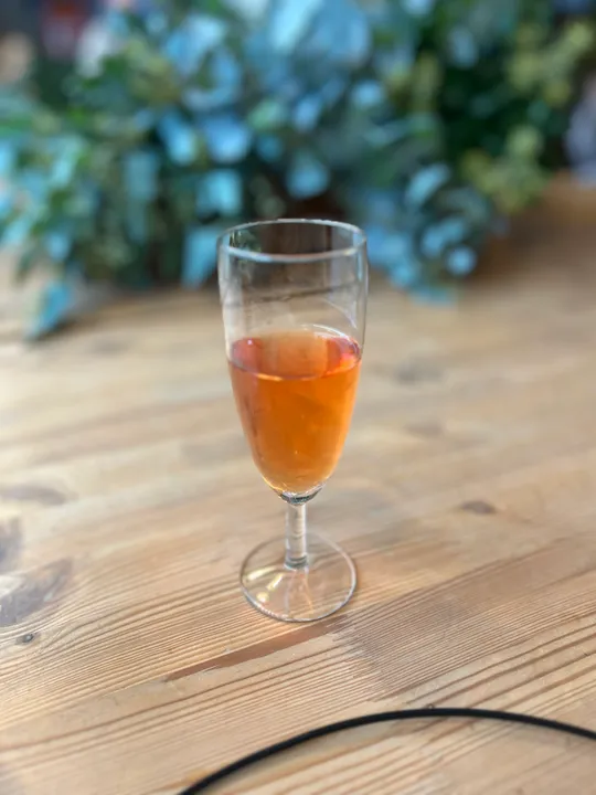 Glass with orange drink on wooden table.