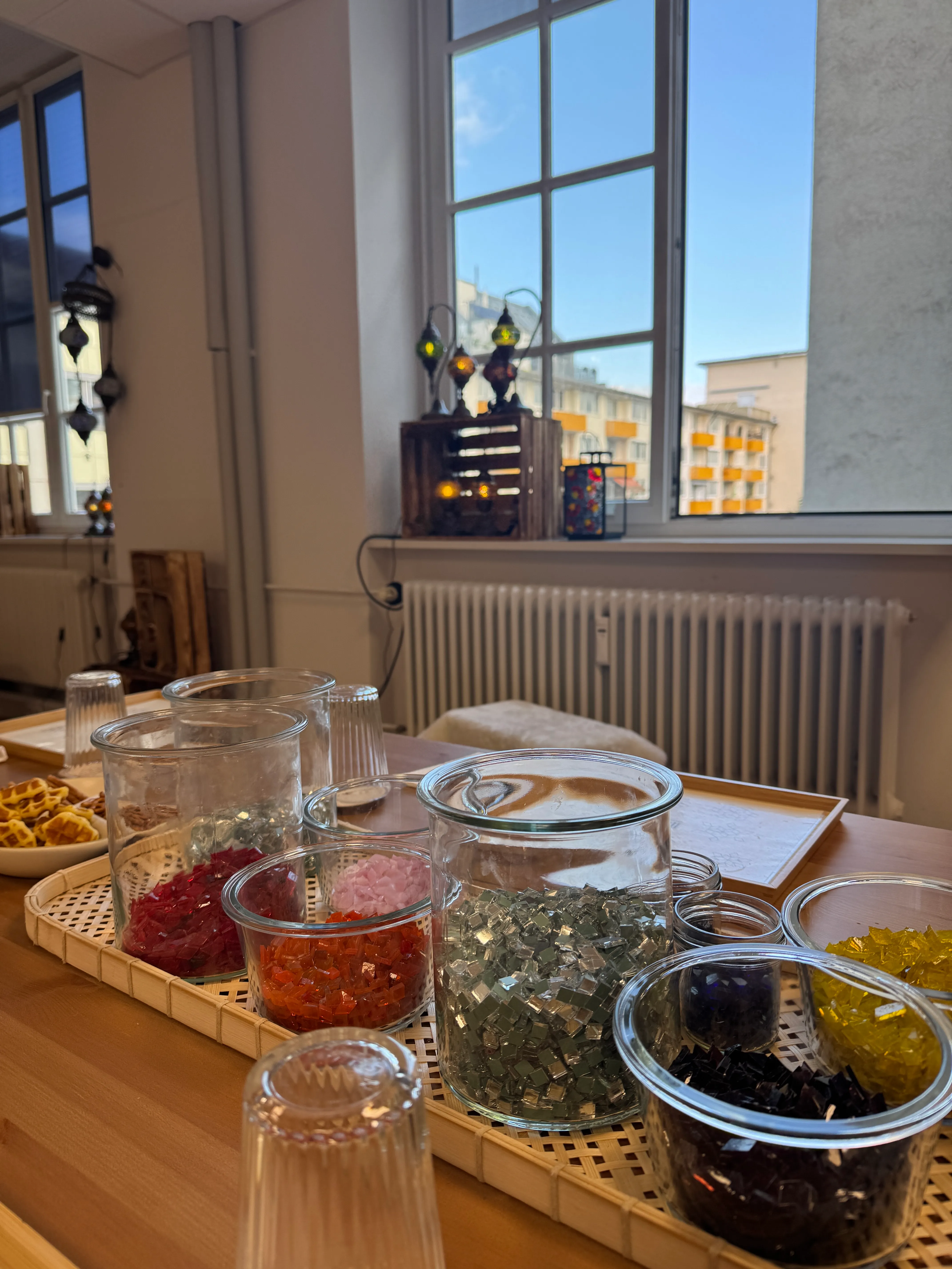 Gläser mit bunten Glasstücken auf Holztisch.