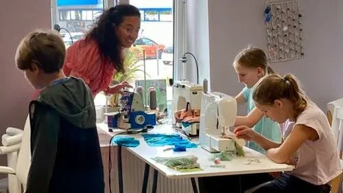 Kinder nähen unter Anleitung im Klassenraum.