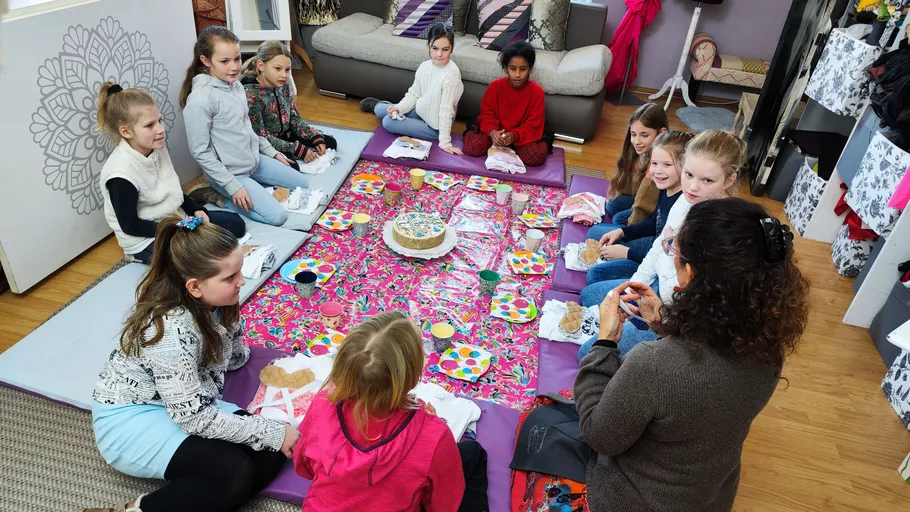 Kinder sitzen um buntes Indoor-Picknick.