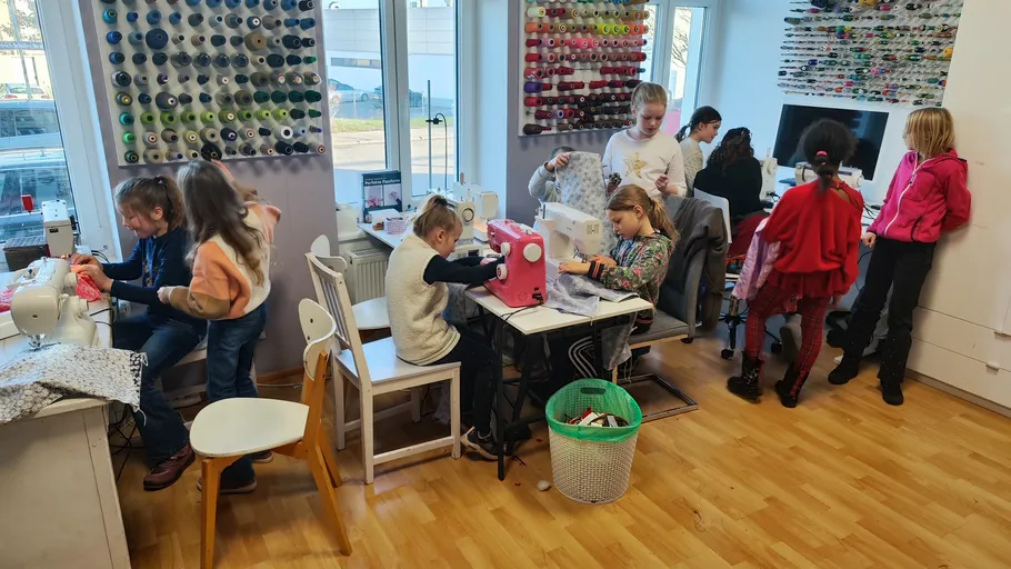 Kinder nähen in einem bunten Klassenzimmer.