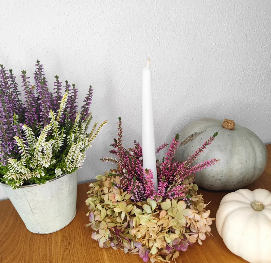 Kerze mit Blumen, Kürbisse auf Holzoberfläche.