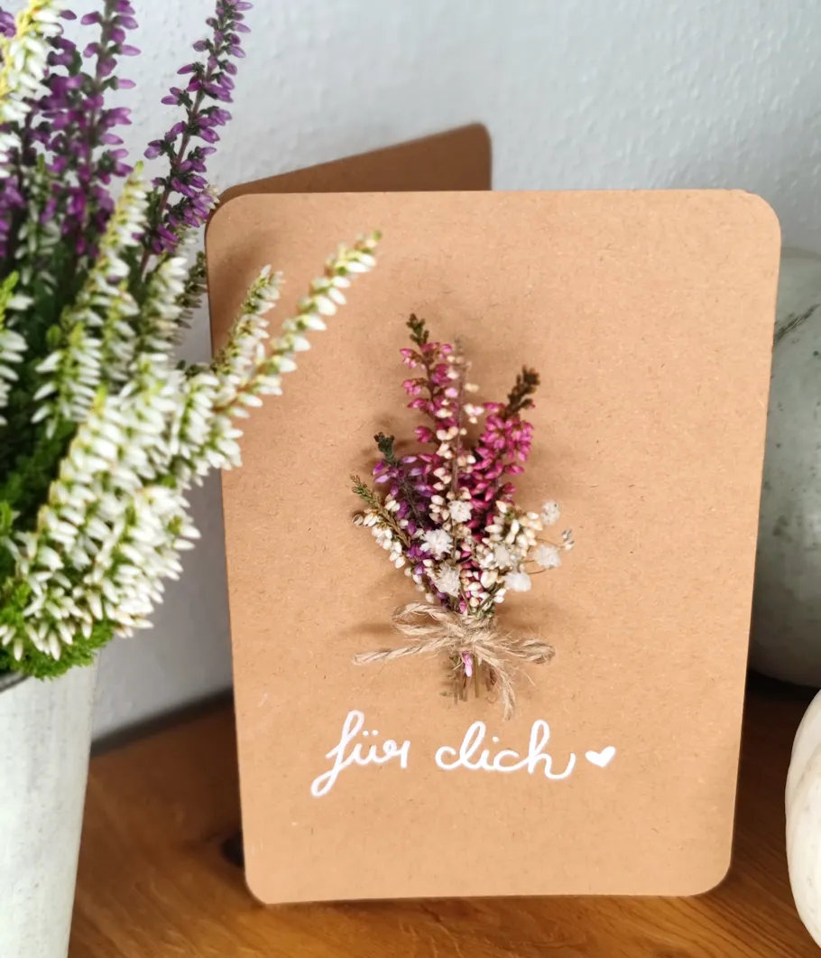 Karte mit getrockneten Blumen auf Holztisch.
