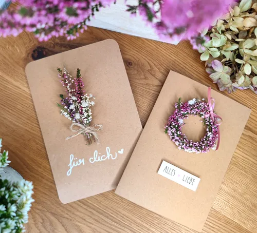 Gebastelte Karten mit Blumen auf Holztisch.