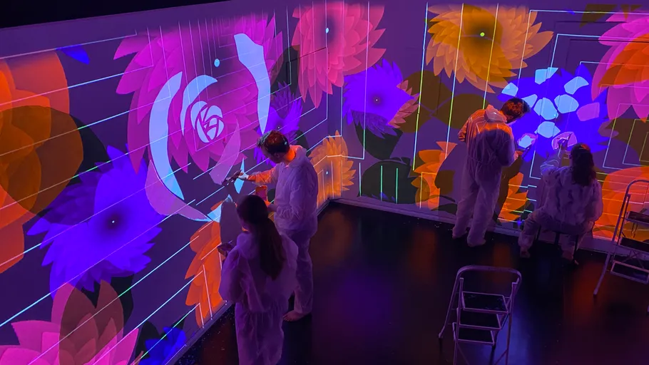 People painting on walls with projected flowers.