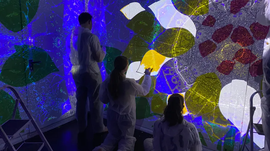 People painting glowing abstract art on wall.