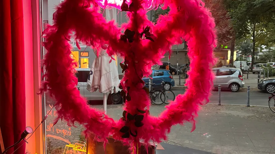 Pink feather heart in window, street outside.