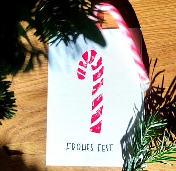 Candy cane and card on wooden table.