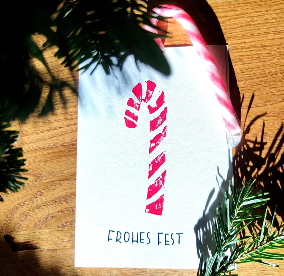 Candy cane and card on wooden table.
