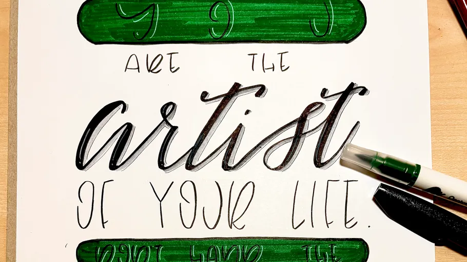 Calligraphy quote on a paper with pens.