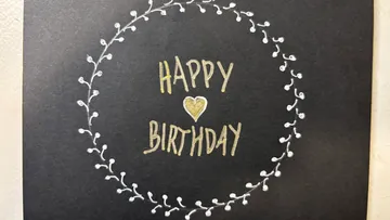 Karte mit 'Happy Birthday' von Kranz umgeben.