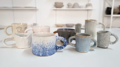 Various handmade mugs on a white table.