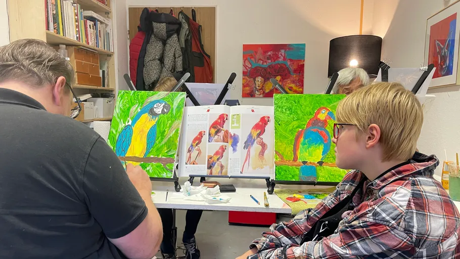 People painting colorful parrot art in studio.
