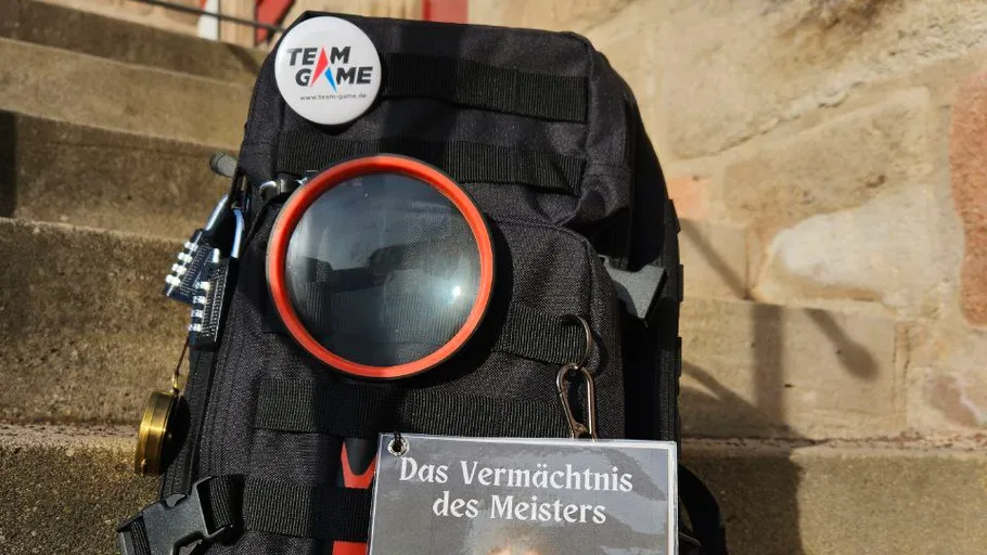 Rucksack mit Lupe und Abzeichen auf Stufen.