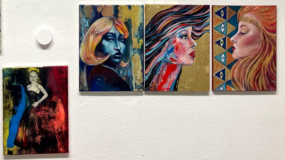 Four colorful portraits of women on a wall.
