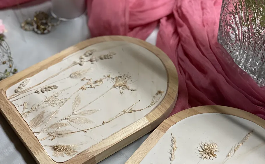 Zwei Holztabletts mit getrockneten Blumendesigns.