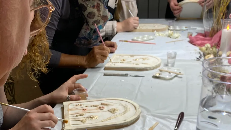 People painting wooden plaques at a table.