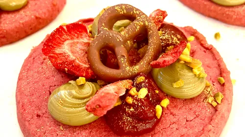 Roter Keks mit Brezel, Erdbeeren und Creme belegt.