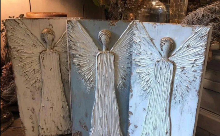 Two carved angel sculptures on wooden panels.