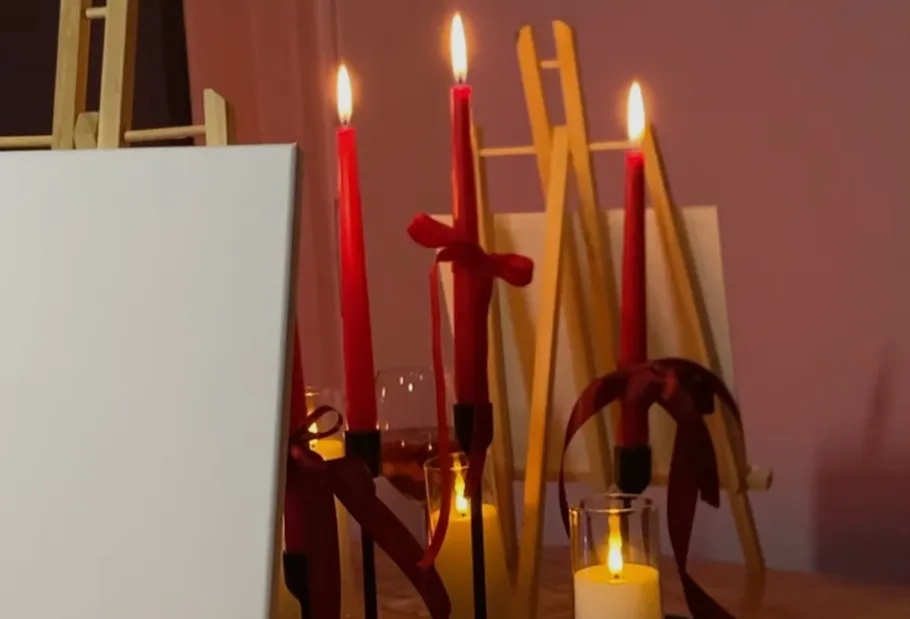 Canvas and lit candles with easels nearby.