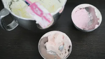 Schüsseln mit Zuckerguss und Spachtel auf Tisch.