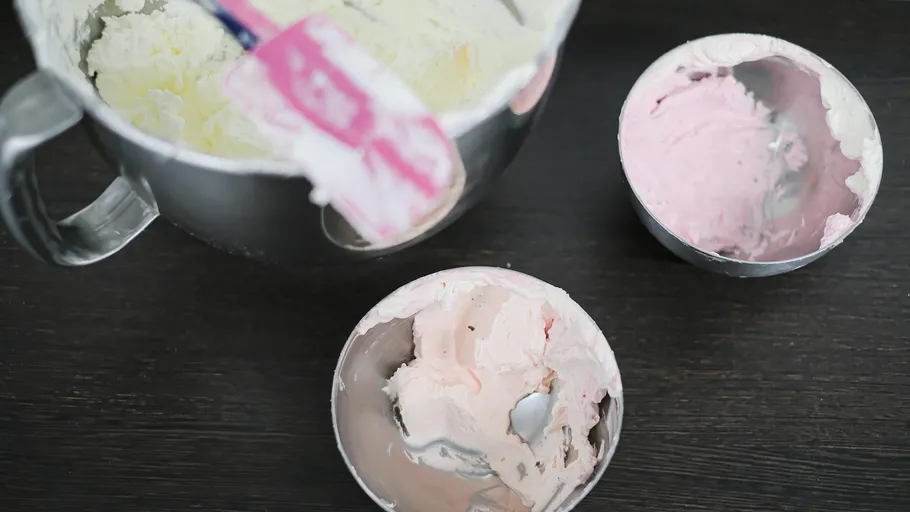 Schüsseln mit Zuckerguss und Spachtel auf Tisch.