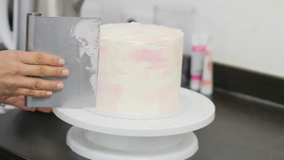 Person glättet Glasur auf Kuchen in Küche.