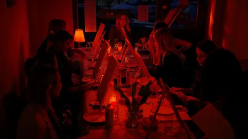 Personen malen an einem schwach beleuchteten Tisch.
