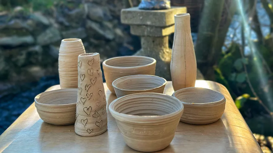 Ceramic vases and bowls on outdoor table.
