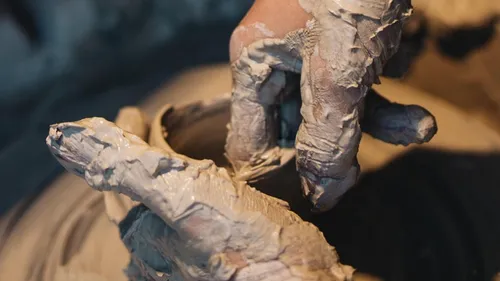 Hands shaping clay on a potter's wheel.