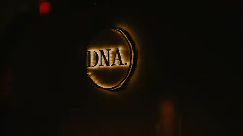 Leuchtendes Schild mit 'DNA.' in dunklem Raum.