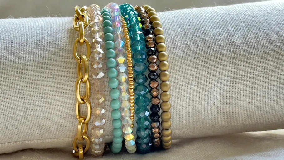 Colorful beaded and chain bracelets on fabric display.