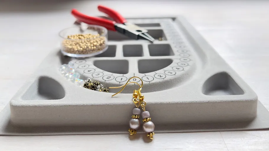 Earrings next to beading board and tools.