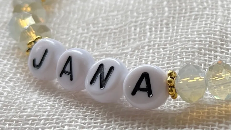 Perlenarmband mit 'JANA' auf Stoff.