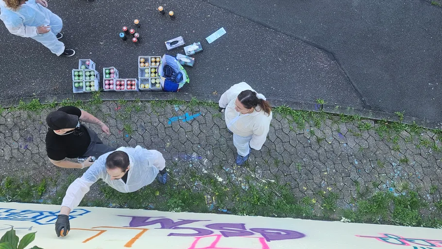 People painting graffiti on outdoor wall.