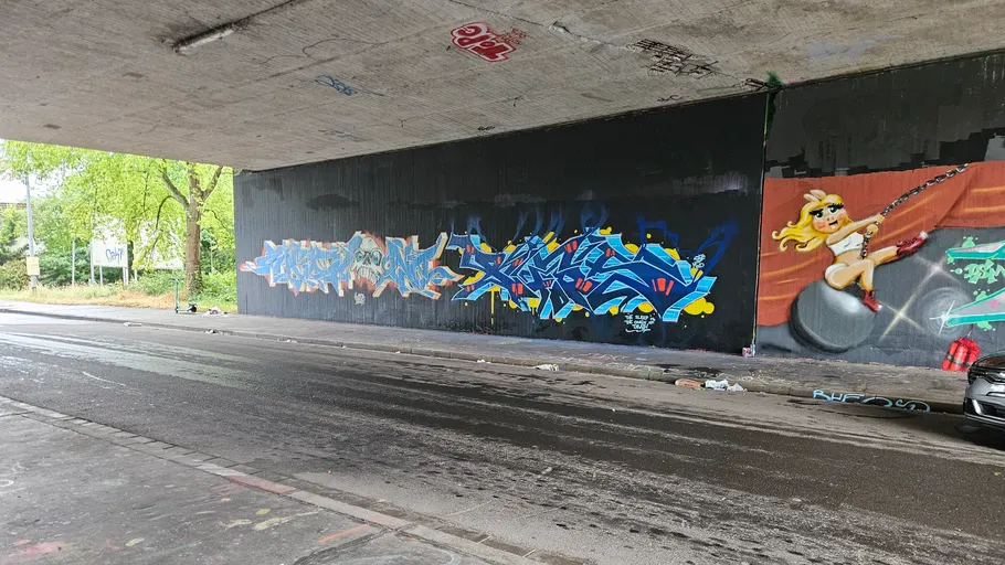 Graffiti an Unterführungswand mit bunten Designs.