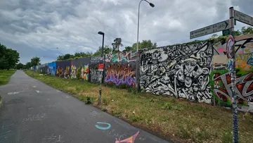 Mit Graffiti bedeckte Wand neben gepflastertem Weg.