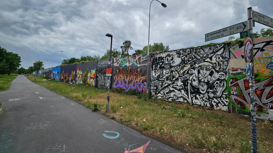 Graffiti-covered wall alongside a paved walkway.