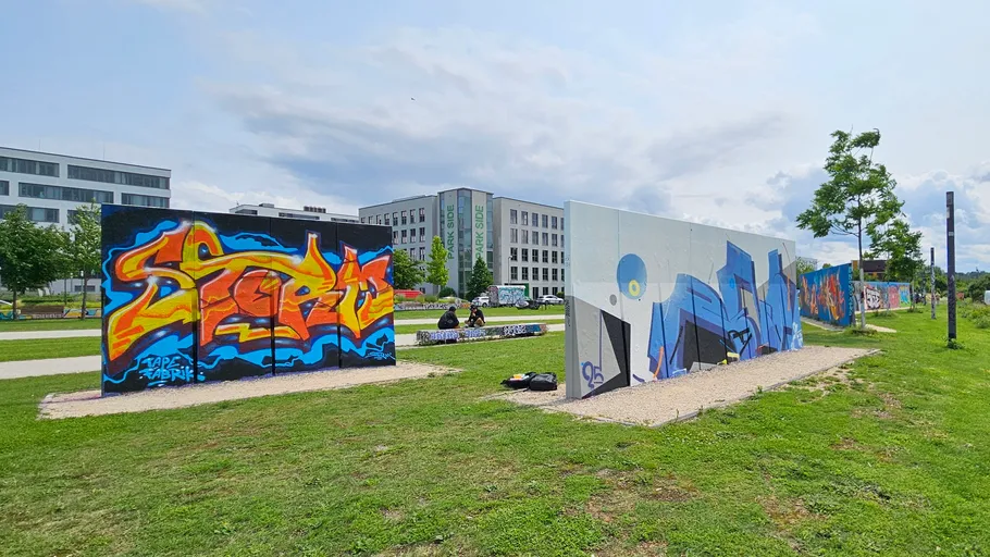 Graffiti-covered walls in grassy urban park.