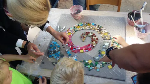 People creating colorful tile mosaic art.